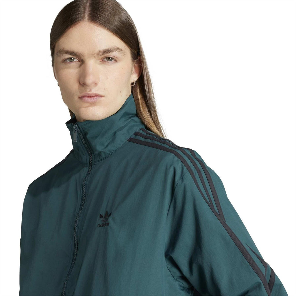 Women’s adidas teal track jacket close-up with high neck, small logo, and sleeve stripes
