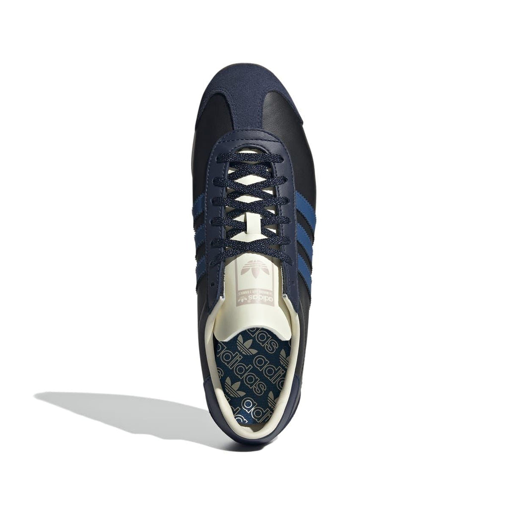 Navy/black lace-up trainer with blue stripes and cream insole label on the tongue