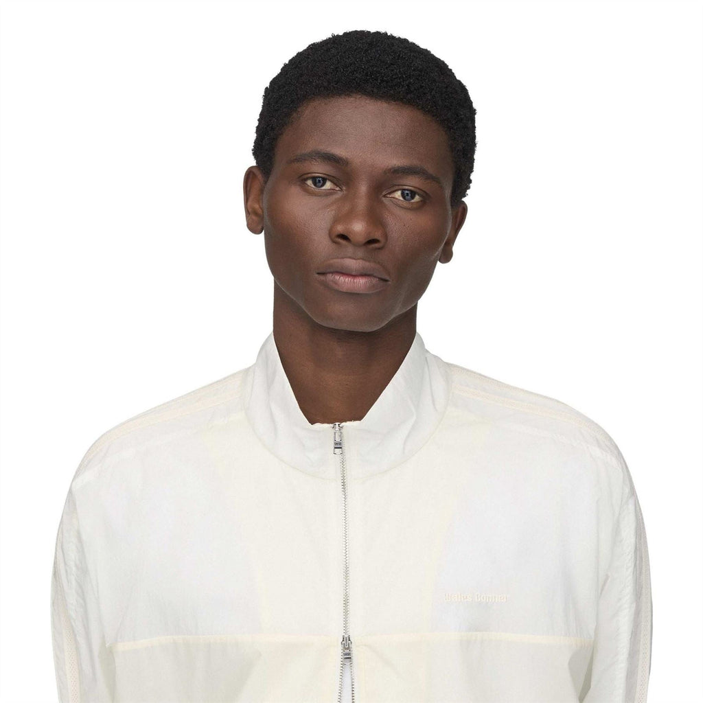 Chalk white track jacket close-up: stand collar and full-zip front with fine panel lines.