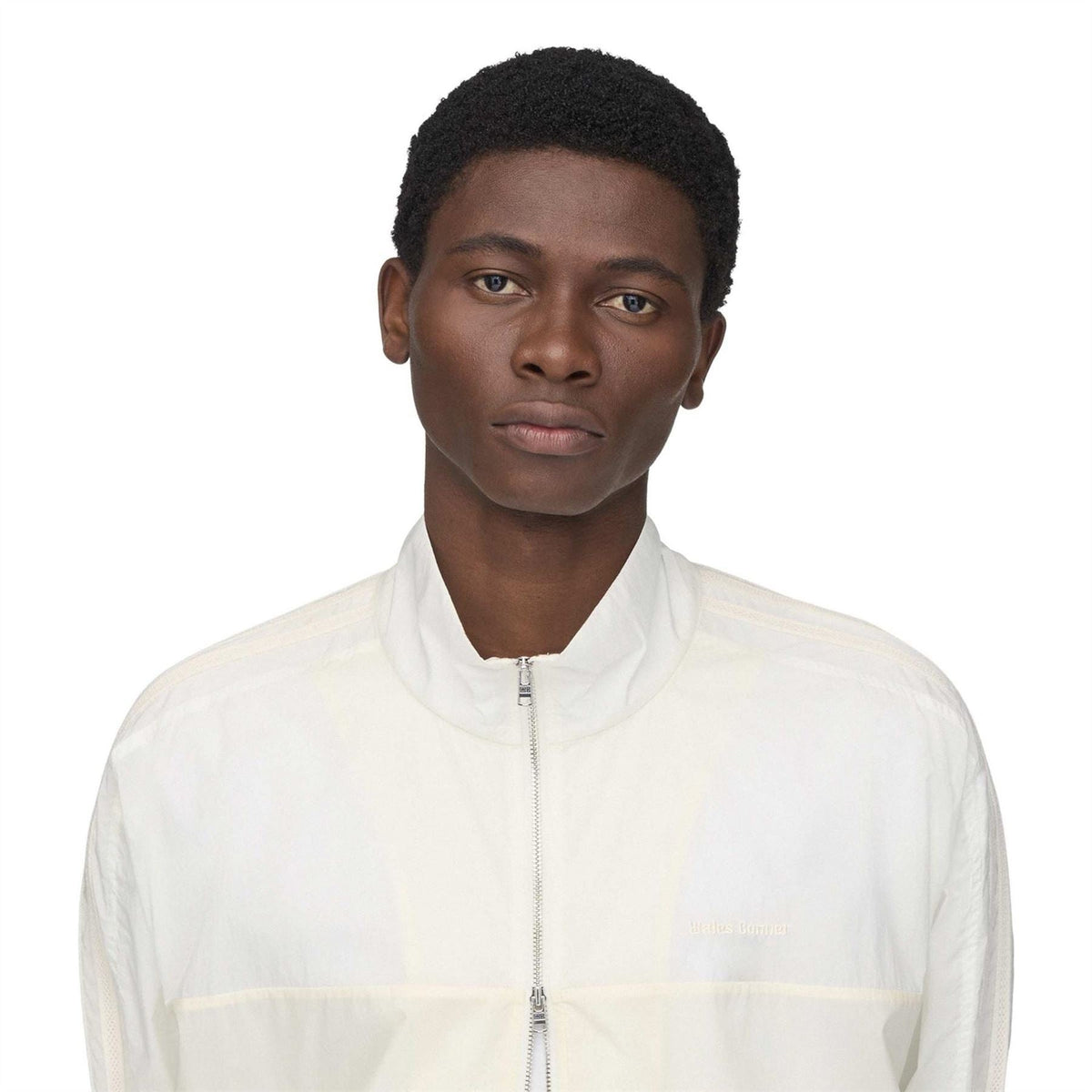 Chalk white track jacket close-up: stand collar and full-zip front with fine panel lines.