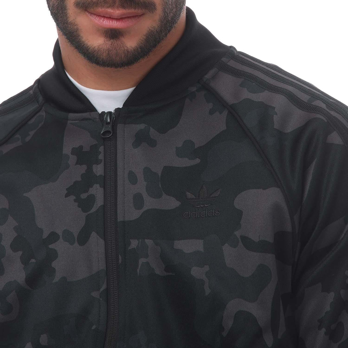 Camo track top close-up: full-zip front, stand collar, adidas logo, black