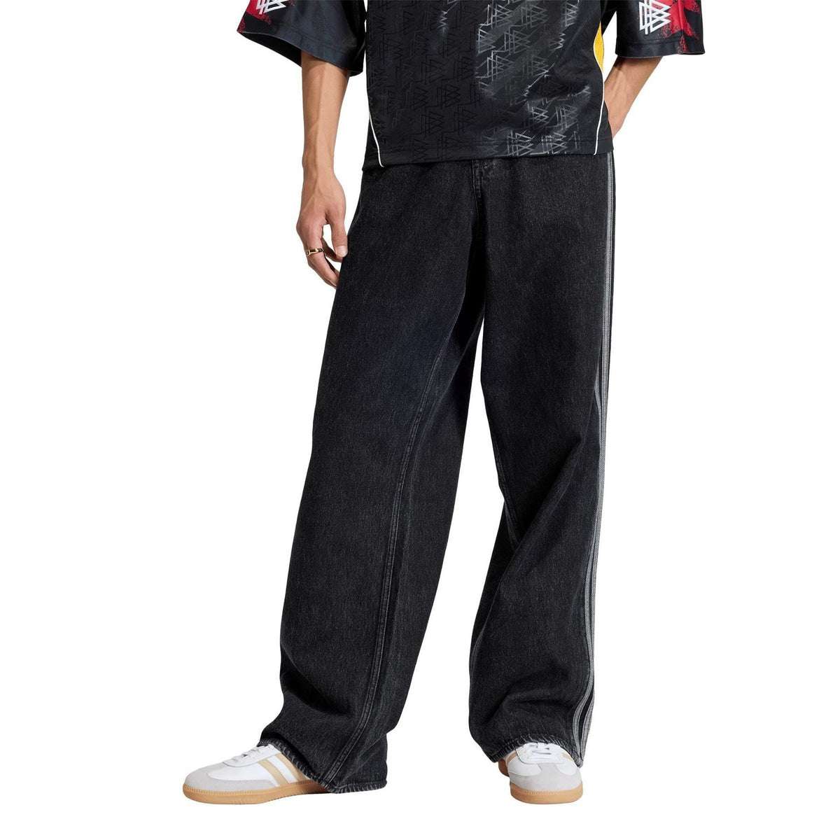 Black wide-leg jeans with cuffed hem and sporty side stripe, worn with sneakers