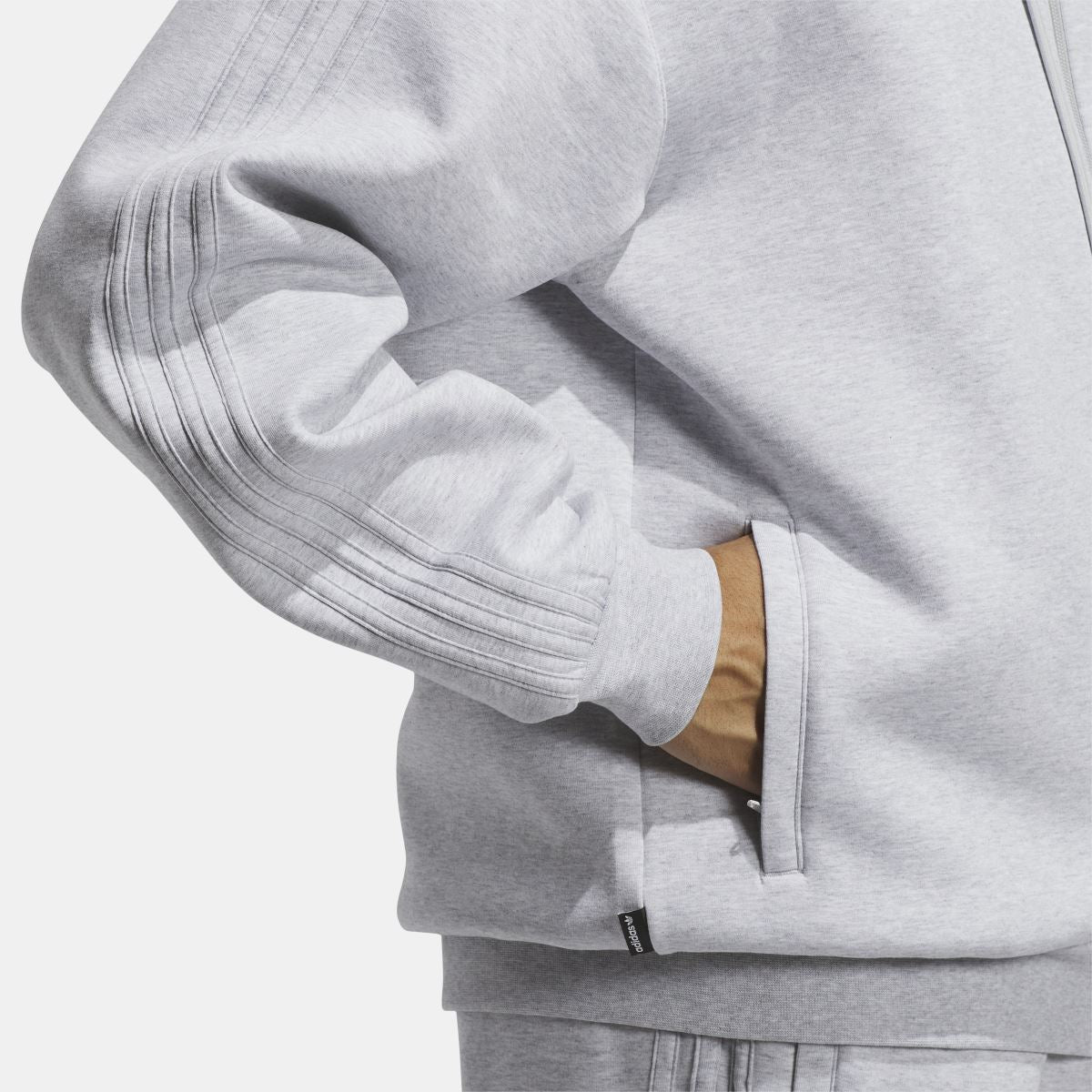 Grey fleece hoodie sleeve close-up with ribbed cuff and pocket seam details.