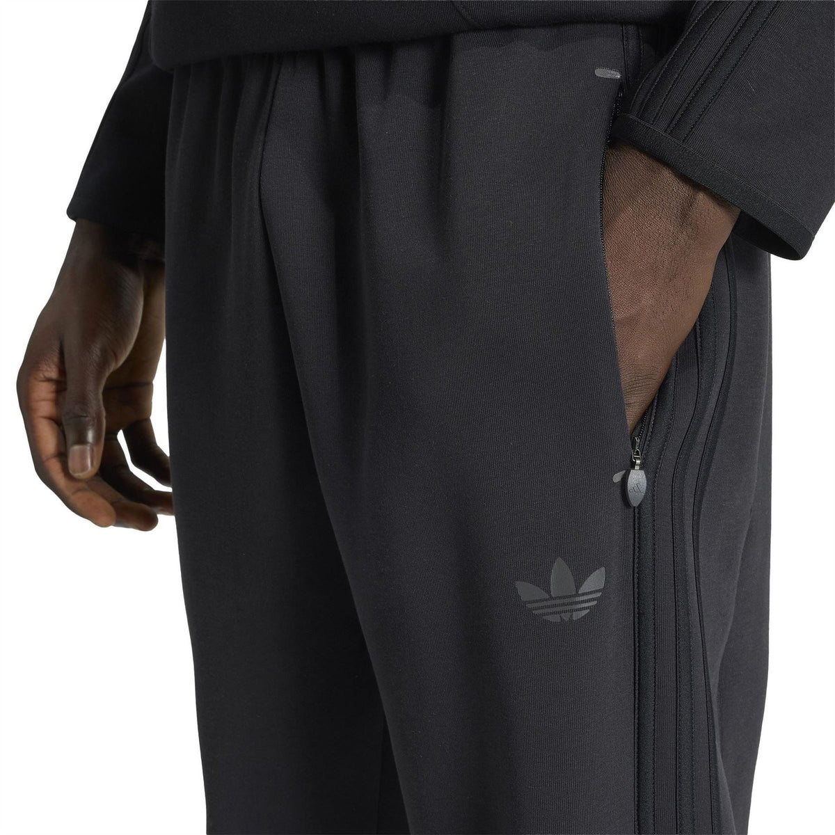 Black track pants close-up of gathered waistband, zip pocket and adidas trefoil logo