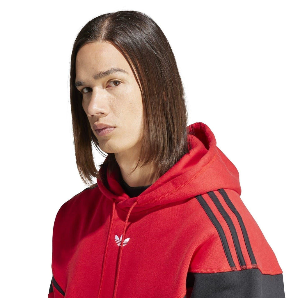 Red hooded sweatshirt close-up with logo on chest and black stripe on sleeve.