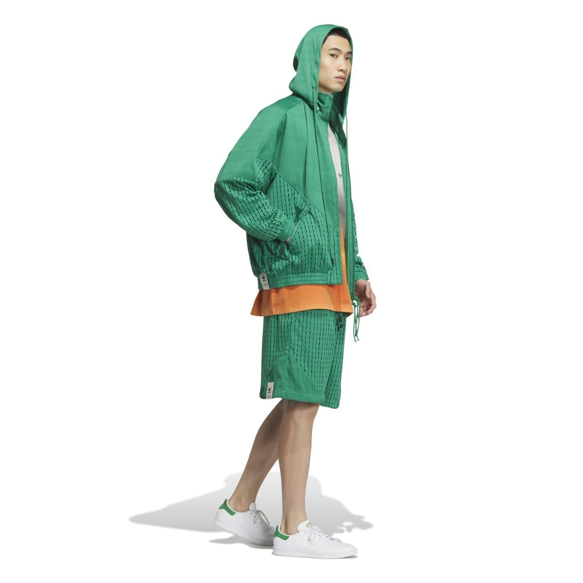 Green hooded zip jacket worn to the side, long sleeves with perforated knit details