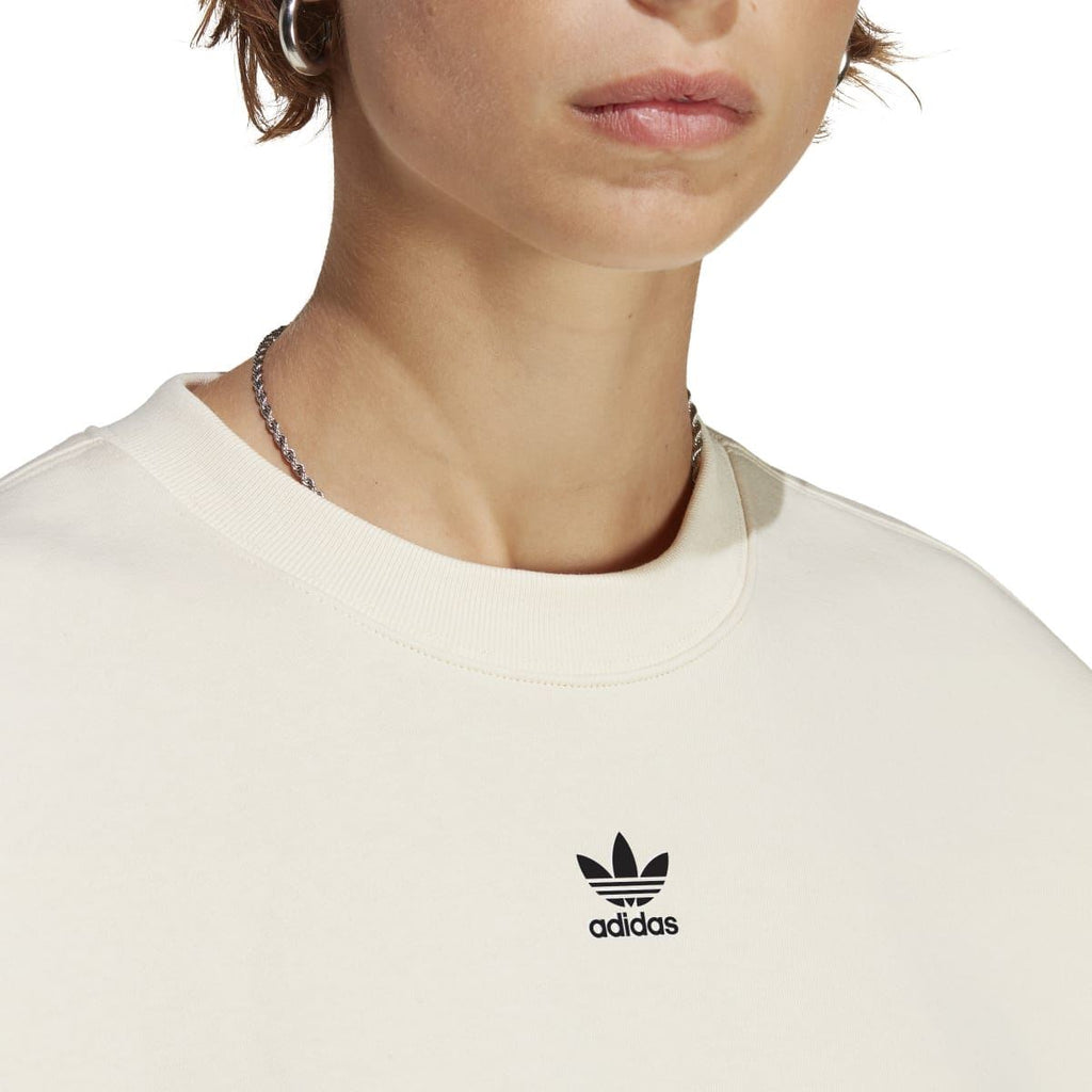 Cream crewneck sweatshirt neckline with adidas trefoil logo at center chest.