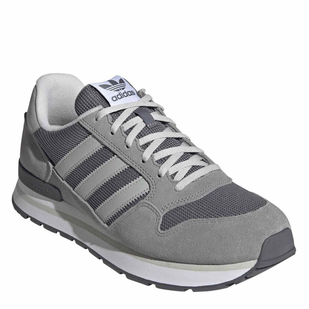 Grey lace-up sneaker with knit tongue, white stripes, and textured side panel