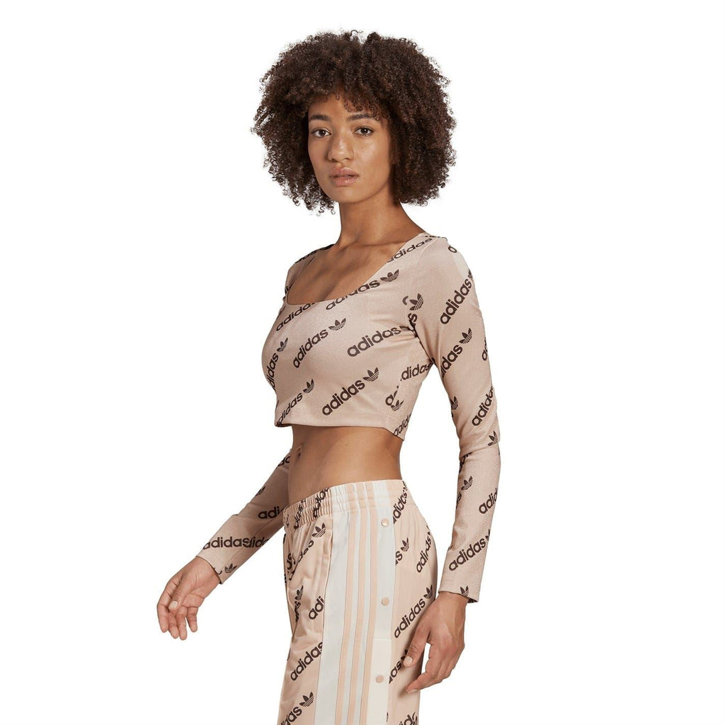 adidas Originals long-sleeve crop top, side view, blush pink with repeating adidas logos