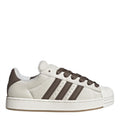 Off-white low-top sneakers with brown three stripes and lace-up front, rubber shell toe.