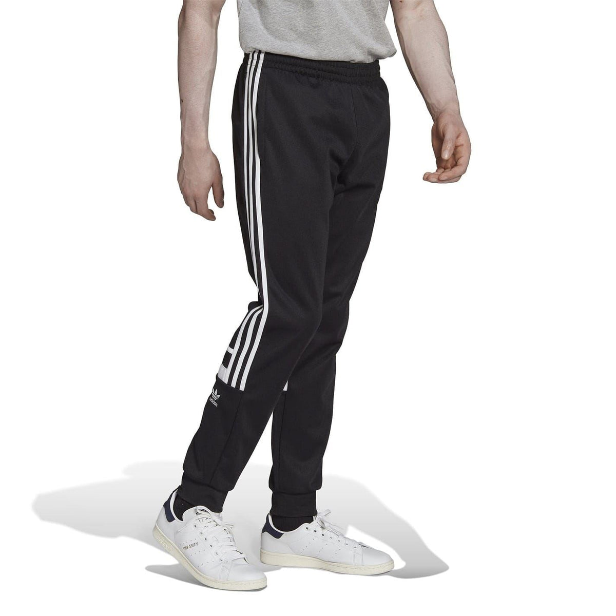 Black tapered joggers with white three-stripe side panels and ribbed ankle cuffs