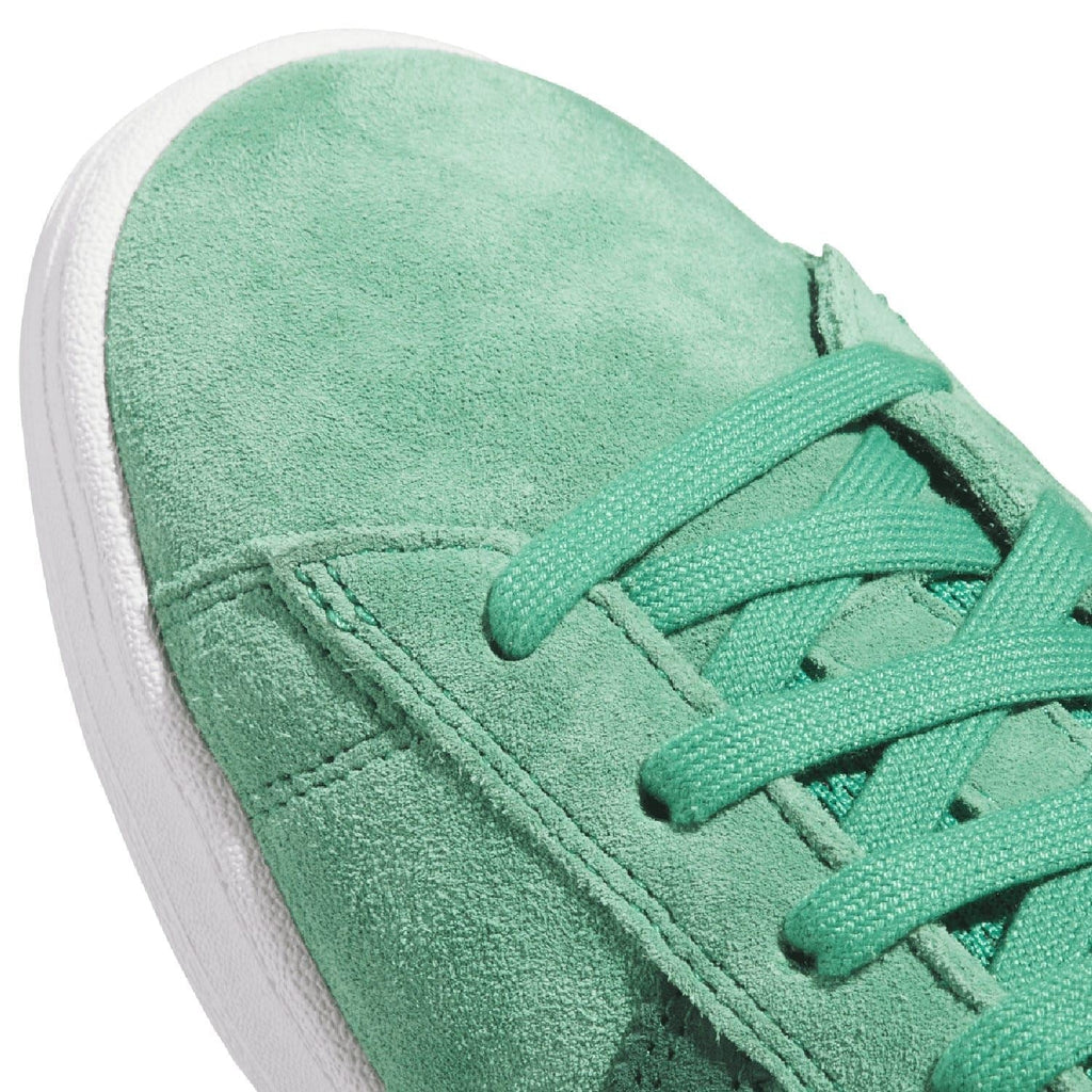 Close-up of green suede trainer with lace-up eyelets and seam stitching