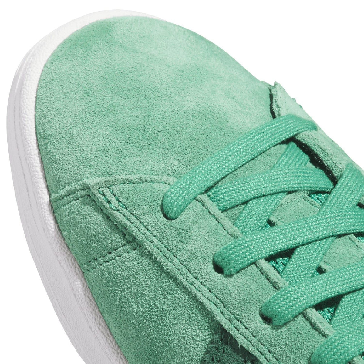 Close-up of green suede trainer with lace-up eyelets and seam stitching