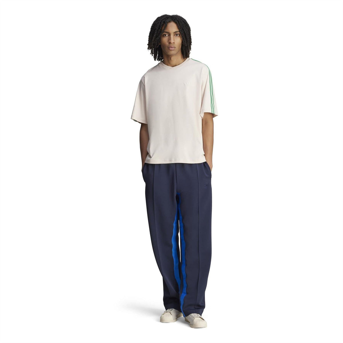 Cream logo T-shirt with green sleeve stripe trim, worn with dark trousers