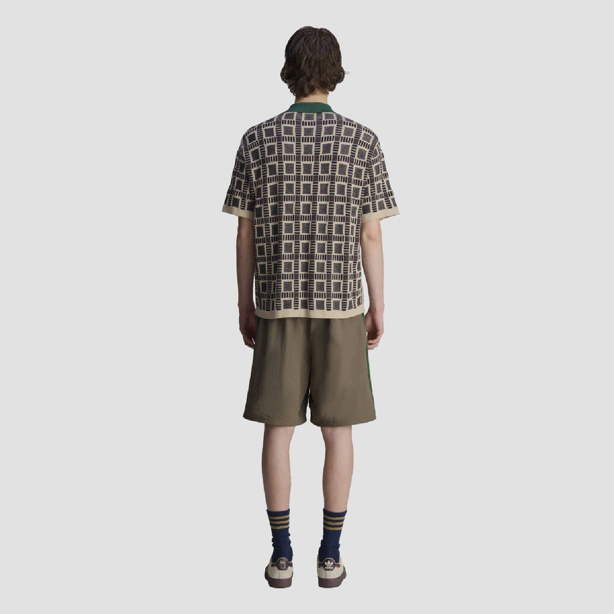 Back view of sand polo shirt with green collar; navy-and-cream geometric grid pattern.