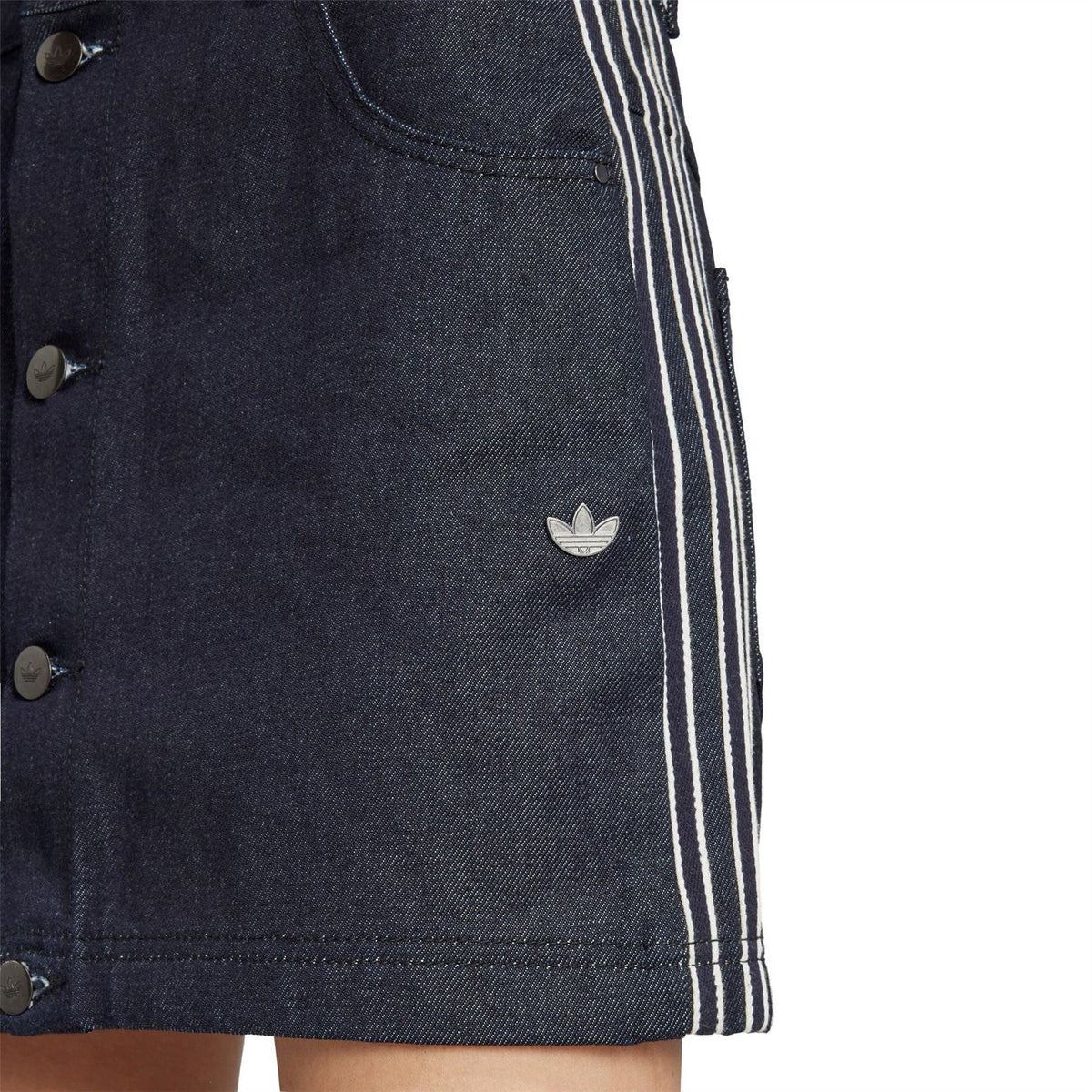 Indigo denim skirt close-up with trefoil patch, button placket, and stitched hem