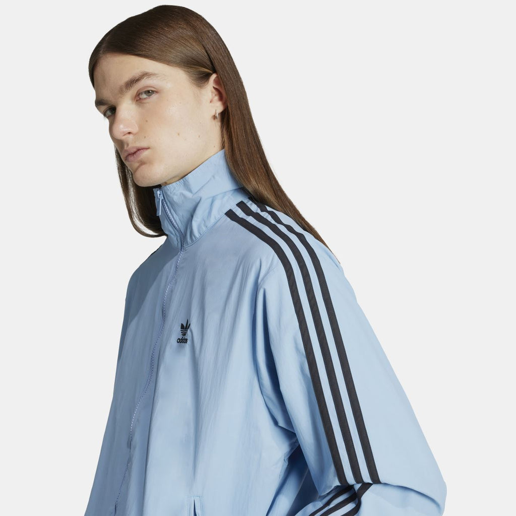 Light blue track jacket detail with adidas logo on chest and black triple stripe shoulder
