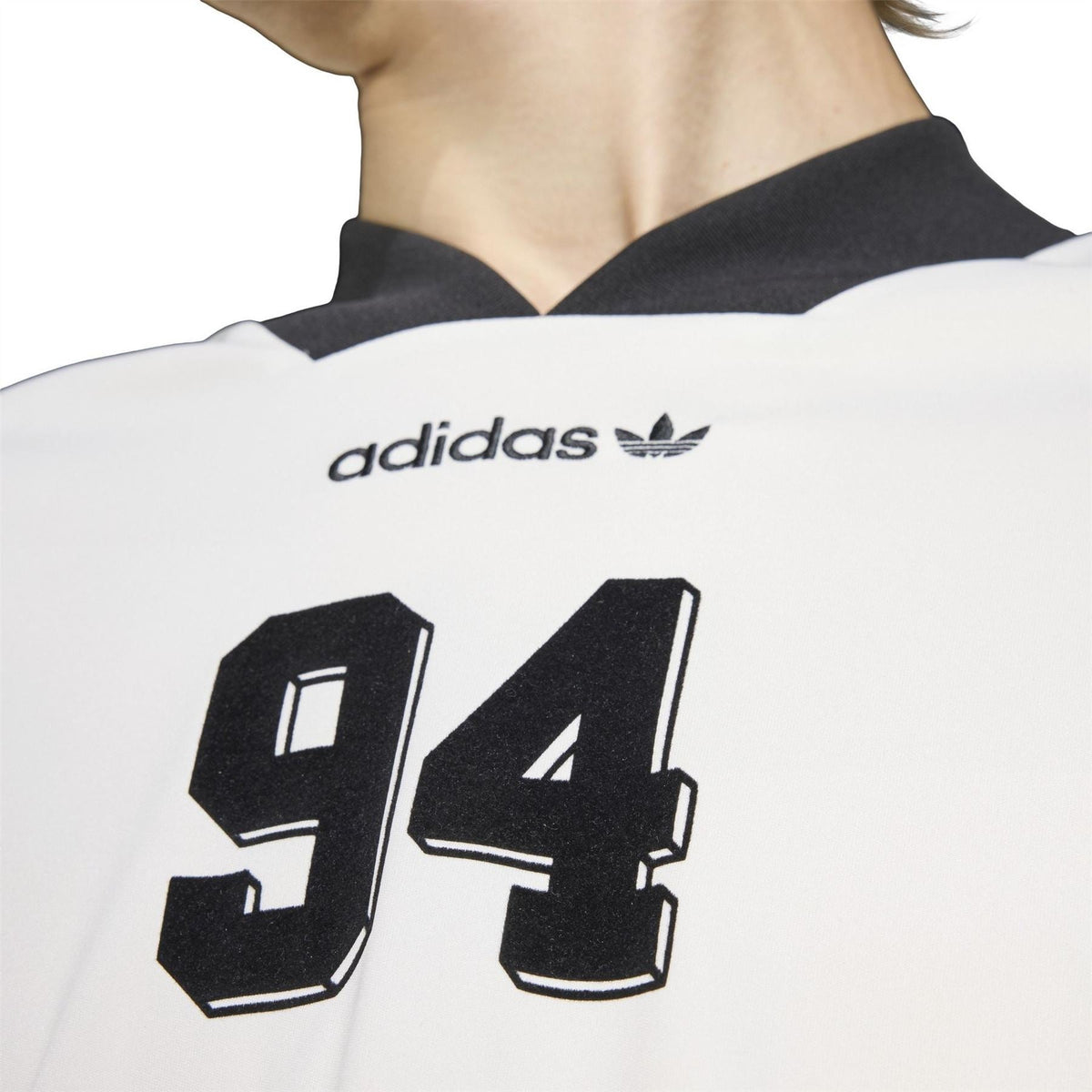 Close-up of Adidas logo and 94 graphic on a white printed shirt with black collar