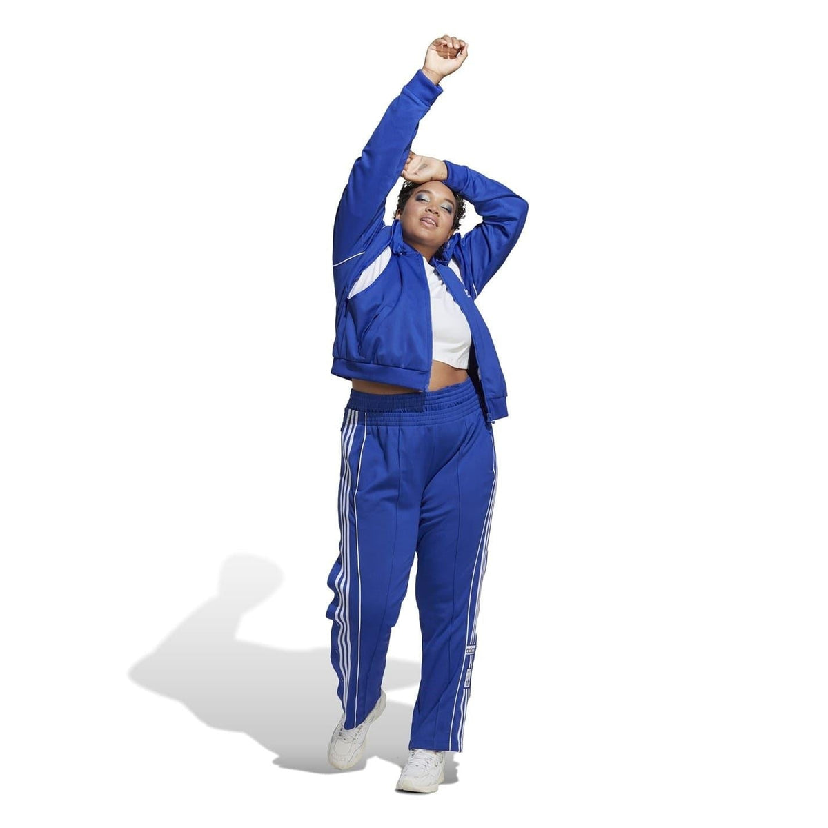 Blue adidas Originals tracksuit set with zip jacket, matching pants, and white stripes