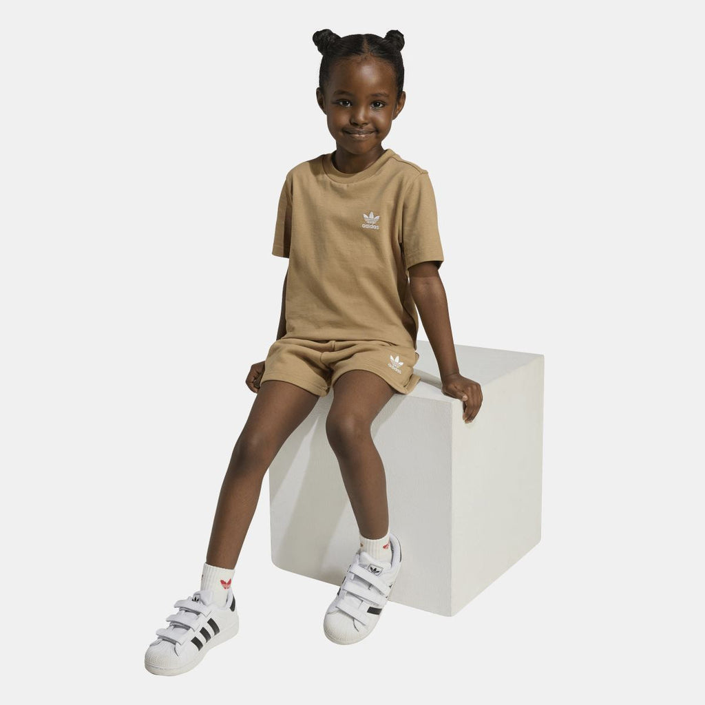 Tan adidas juniors T-shirt and shorts set on model, sitting pose; logo tee and shorts
