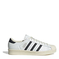 White low-top sneakers with black three-stripe panels, lace-up, shell toe