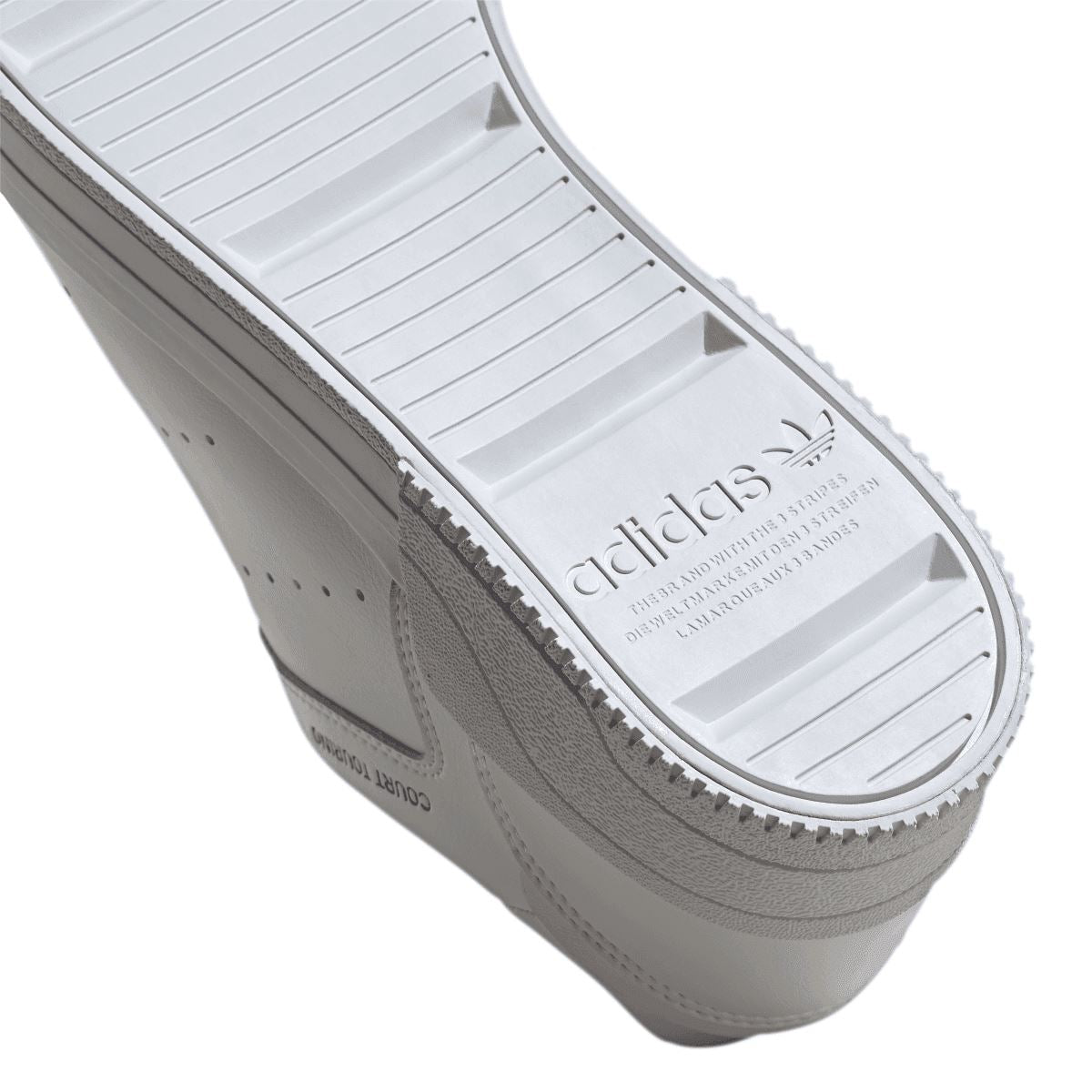 Close-up of white Court Tourino outsole tread with adidas logo and traction grooves.