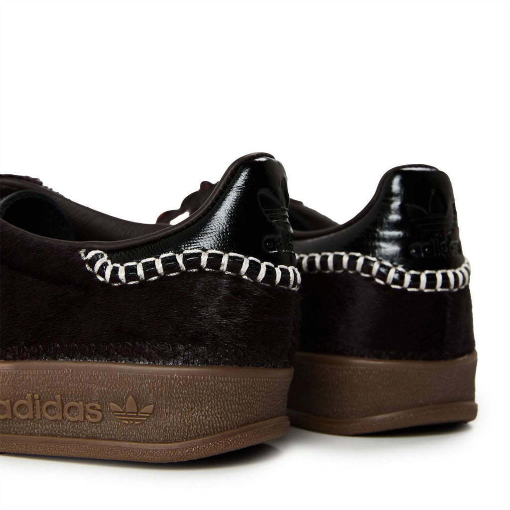 Close-up of black pony Gazelle heel with chain trim, embossed logo on side, gum sole.