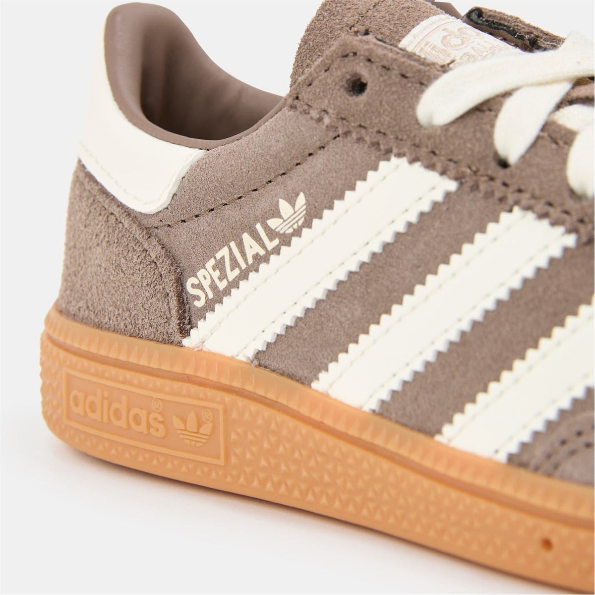 Brown suede adidas SPEZIAL low-top sneakers close-up with white stripes and gum sole