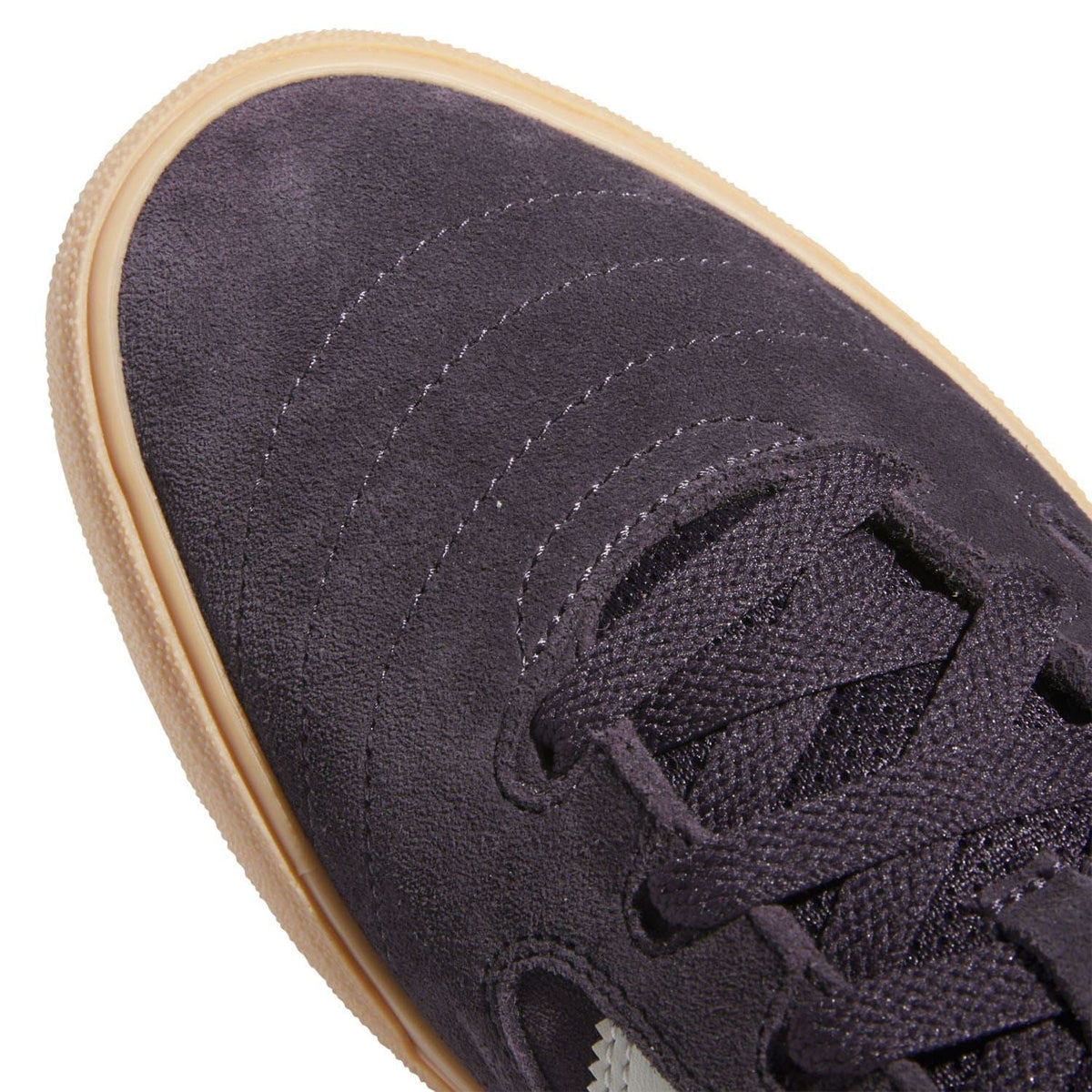 Close-up of dark suede upper with black laces and stitched toe cap