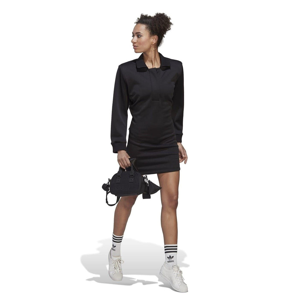 Black long-sleeve mini polo dress on model, standing pose with front button placket.
