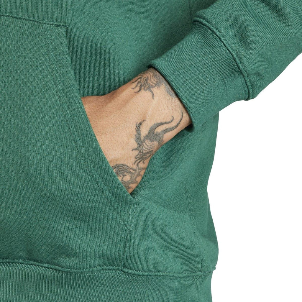 Green hoodie sleeve and pocket area with visible tattoo on wearer's arm