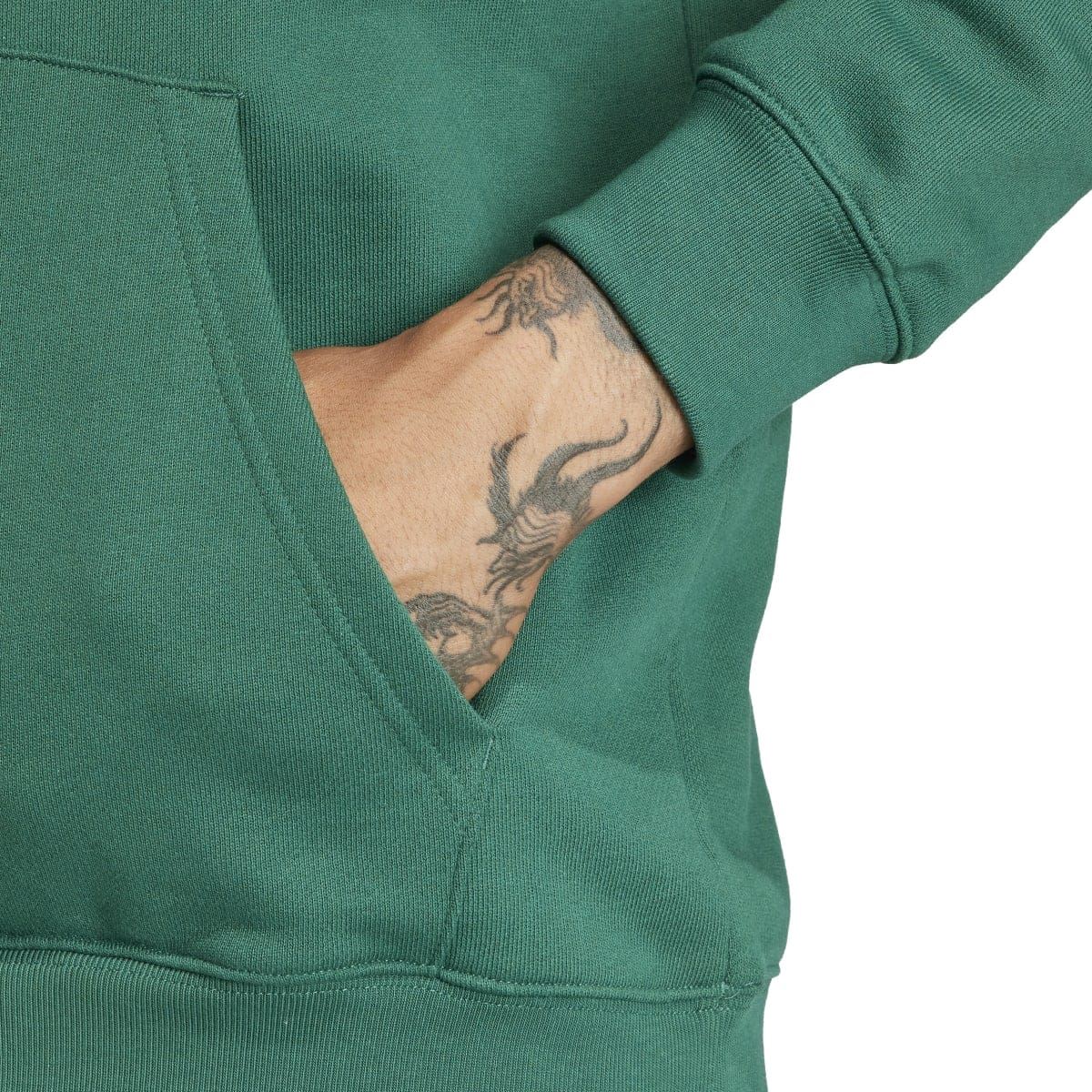 Green hoodie sleeve and pocket area with visible tattoo on wearer's arm
