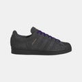 Black low-top Adidas Originals sneakers with purple laces and side stripe detail