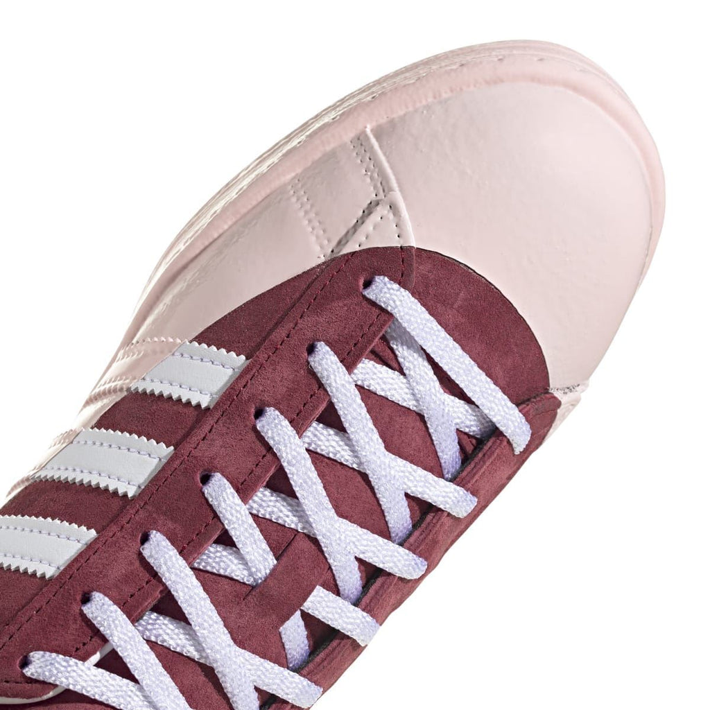 Front view low-top sneaker with burgundy suede panels, off-white leather, and white laces