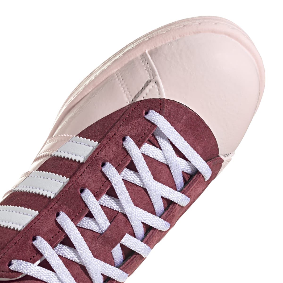 Front view low-top sneaker with burgundy suede panels, off-white leather, and white laces