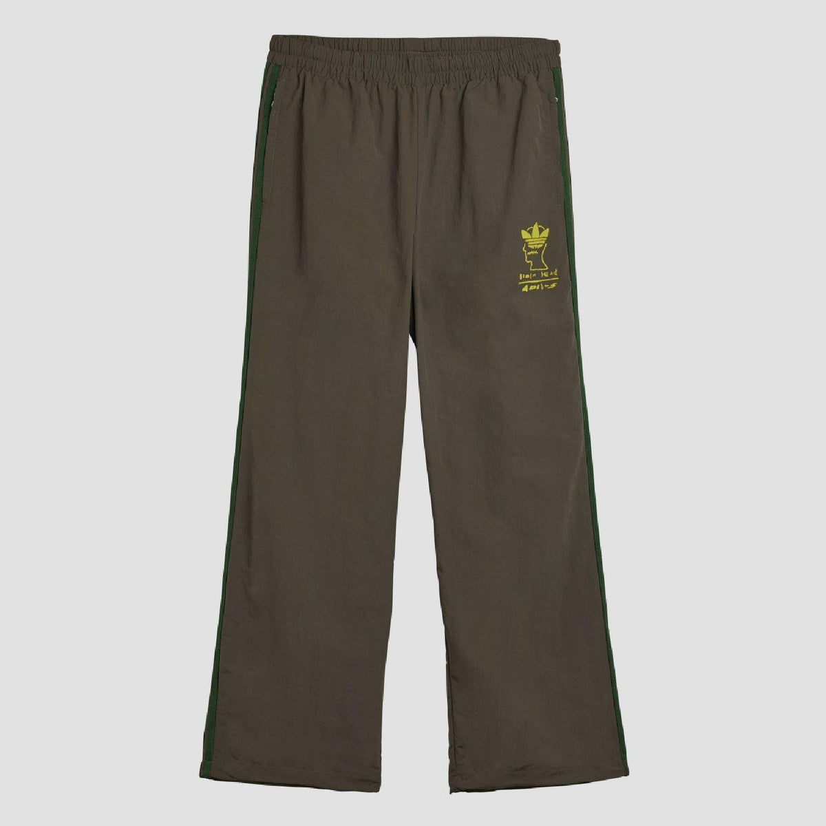 Chocolate track pants with elastic waist, green side stripes, small yellow logo patch