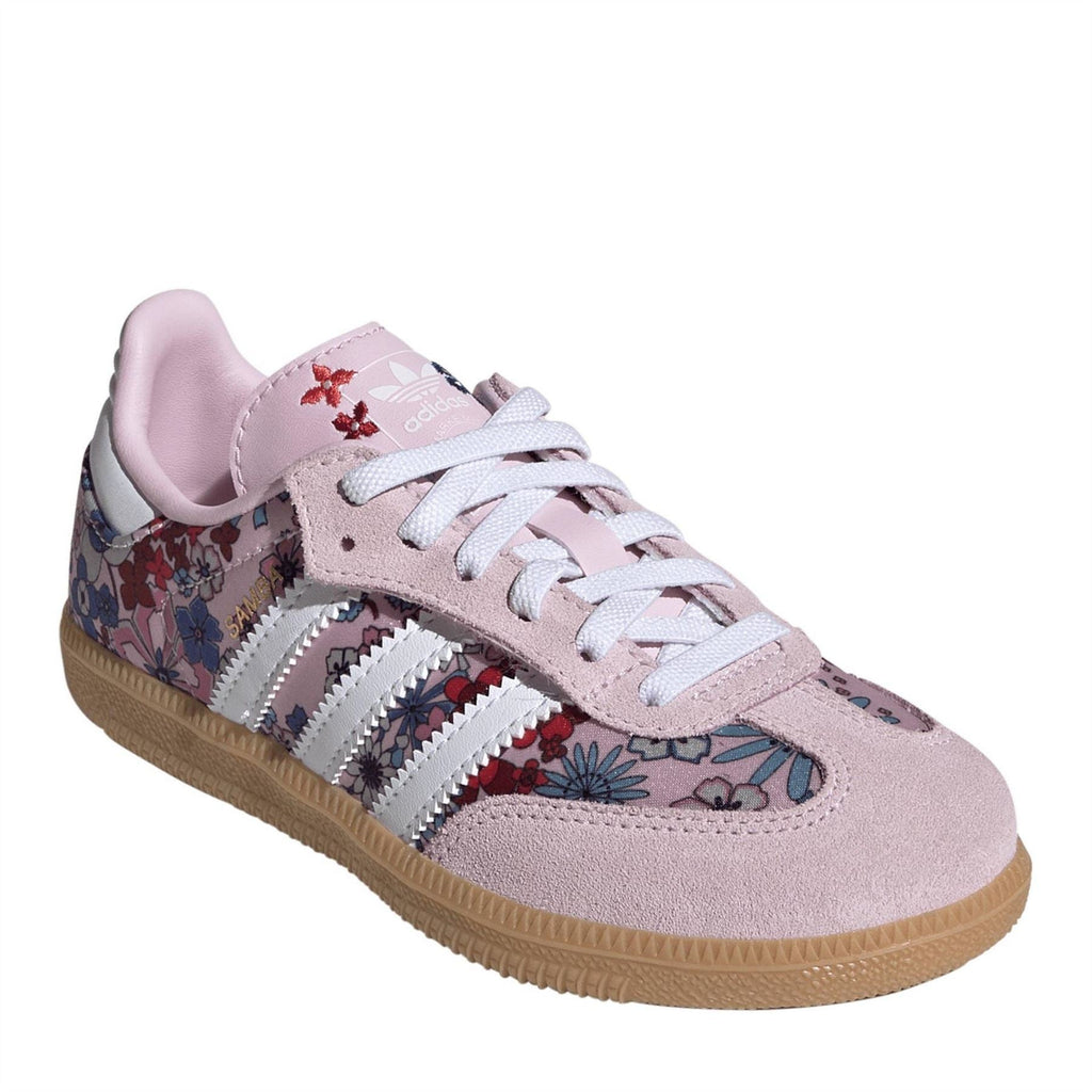 Pink suede low-top sneakers with floral side panels, white stripes, and lace-up.