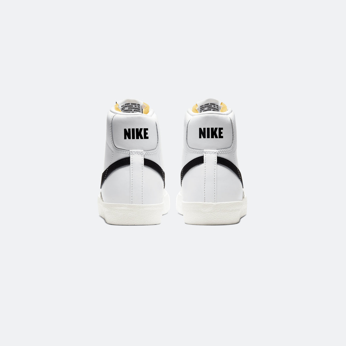 White Nike Blazer Mid '77 sneakers with black heel panel and 'NIKE' branding