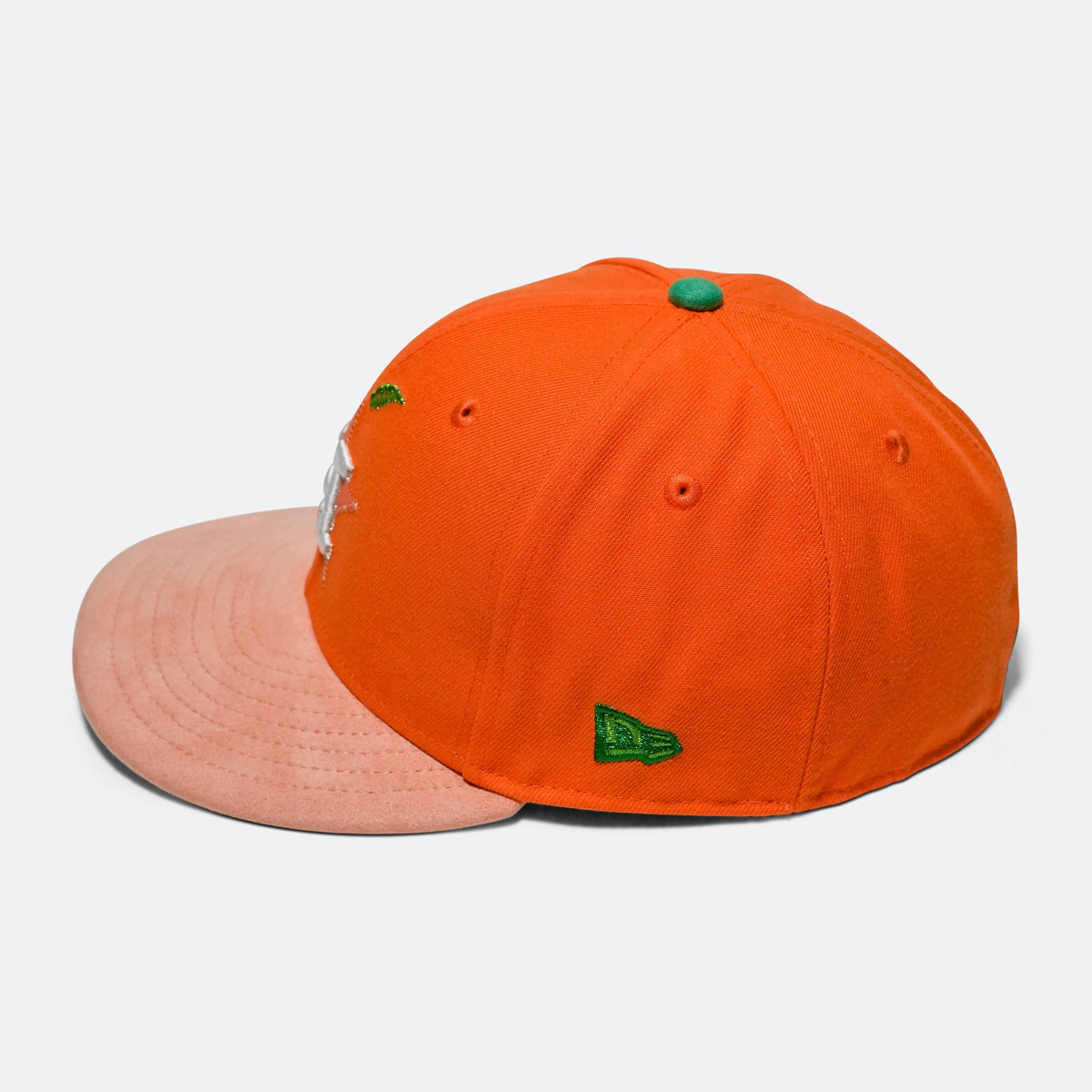 Orange baseball cap with pink brim, green logo patch, and small side detail