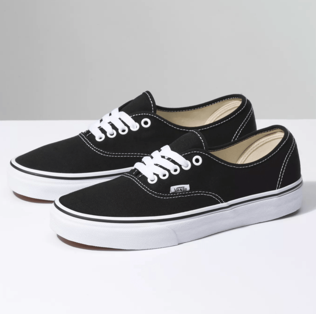 Black canvas low-top sneakers with white laces, beige interior lining