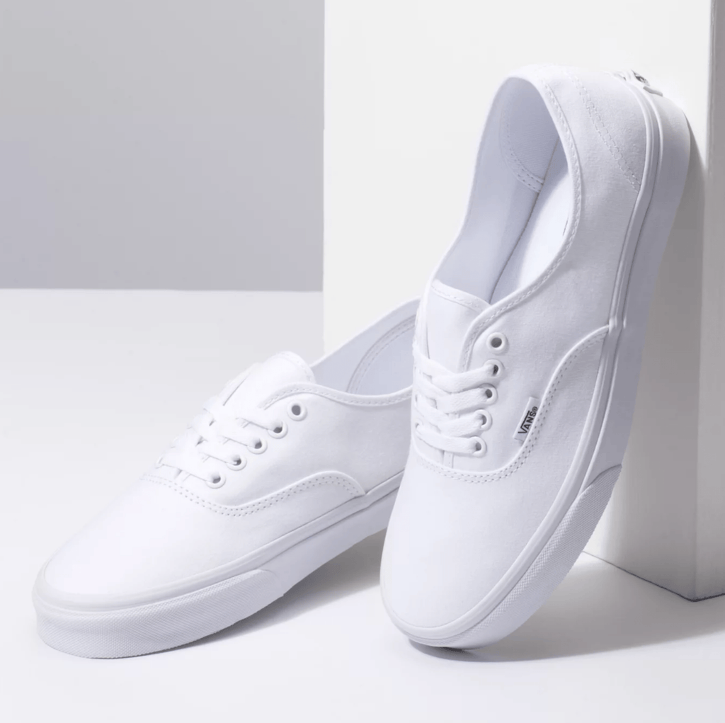 White low-top sneakers with padded collar, lace-up front, and Vans side tag