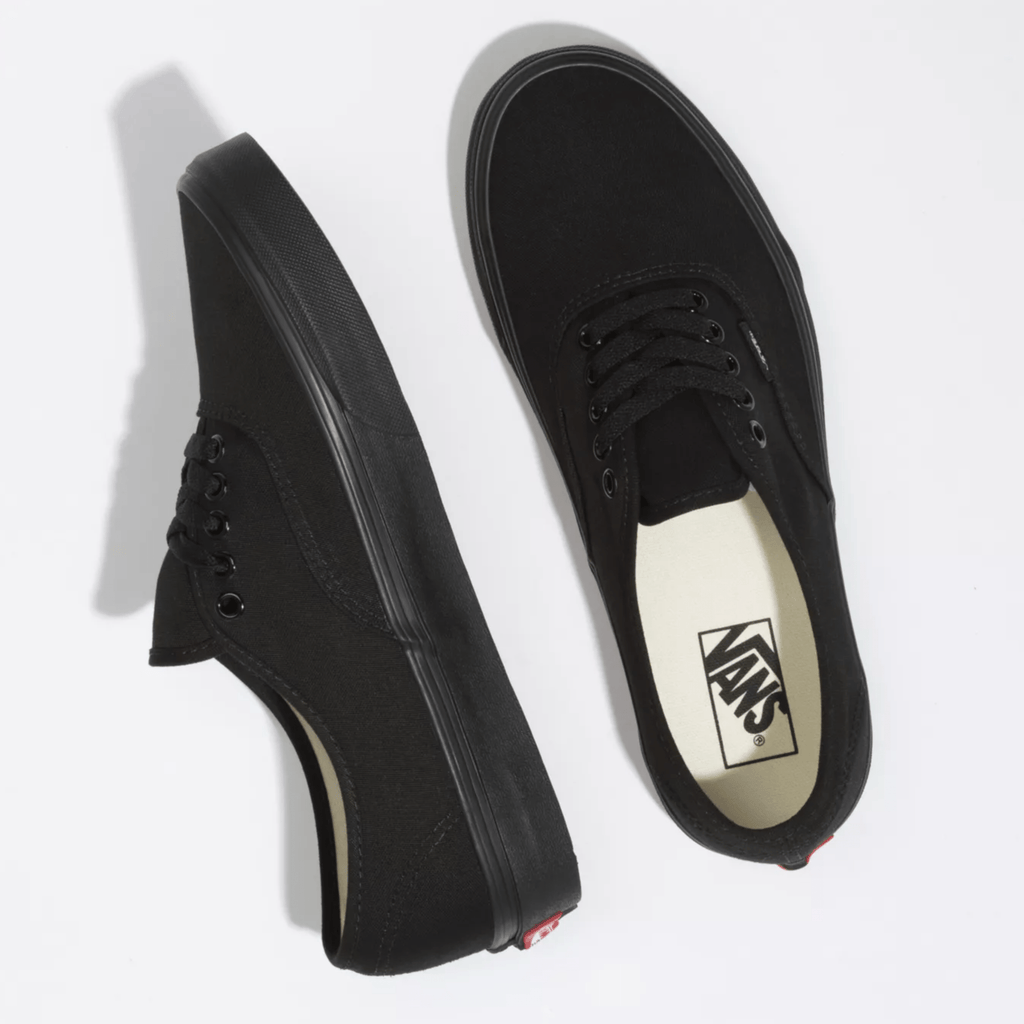 Black low-top sneaker pair side view with Vans logo on light insole