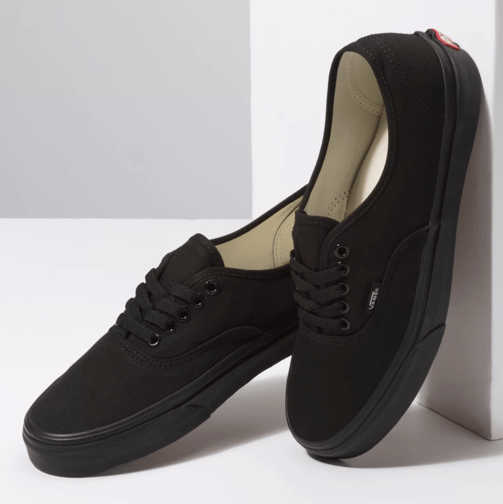 Black low-top lace-up sneakers with padded collar and Vans logo on tongue