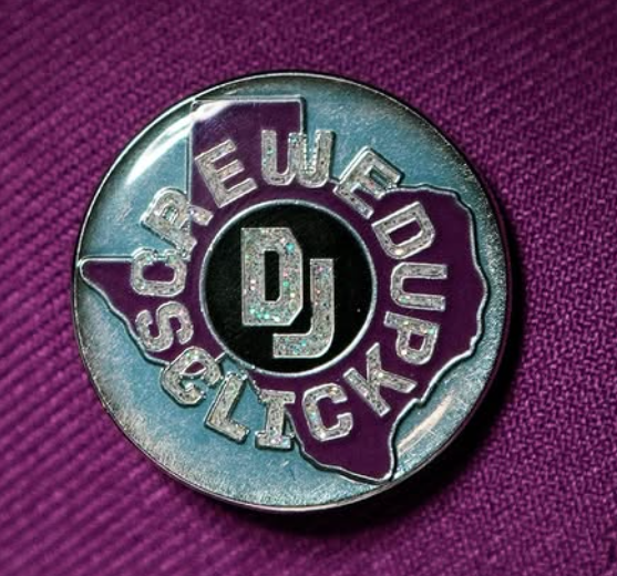 Close-up of a round metal pin badge on a purple baseball cap