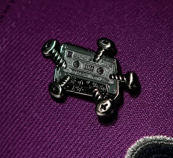 Close-up of a DJ equipment patch on a purple baseball cap