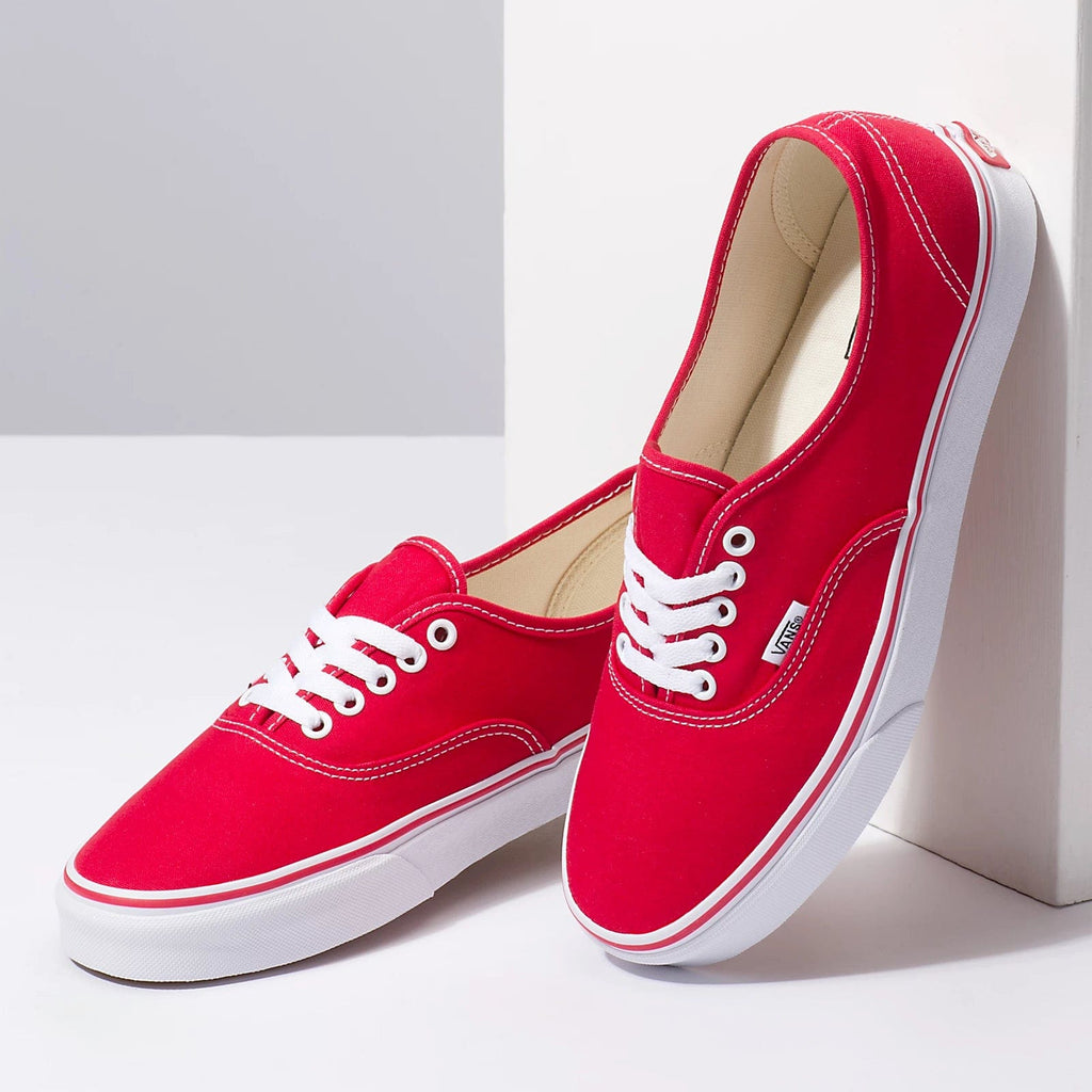 Red low-top sneakers with beige interior lining, white stitching, and lace-up front
