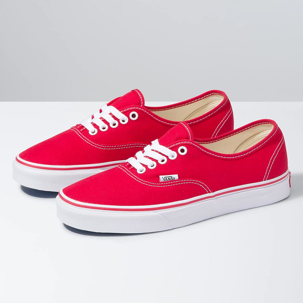 Pair of red low-top lace-up sneakers with white laces and Vans side patch