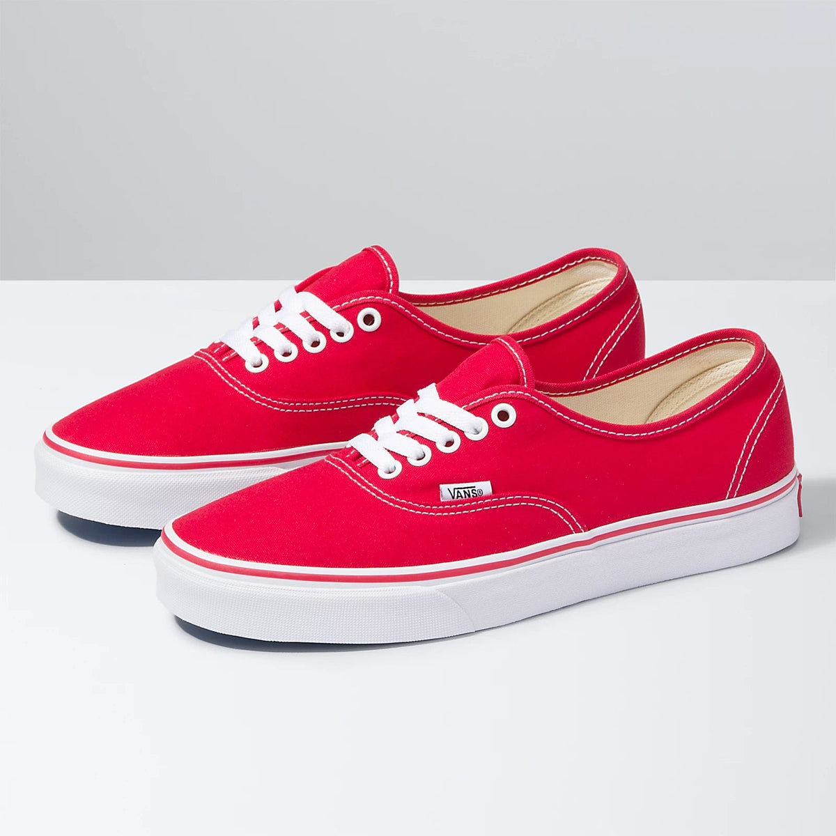 Pair of red low-top lace-up sneakers with white laces and Vans side patch