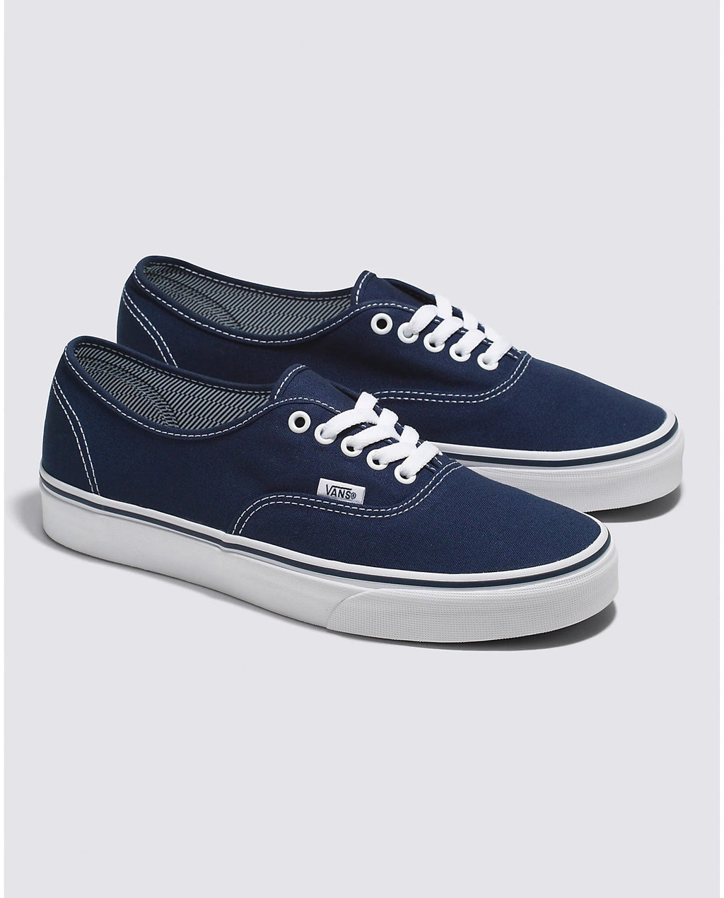 Pair of navy low-top lace-up sneakers with white laces and Vans side patch
