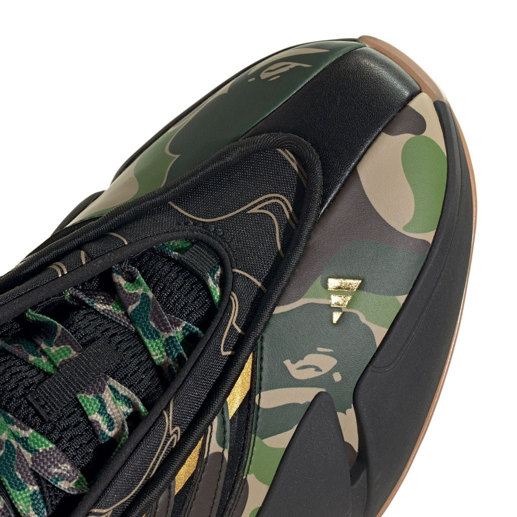 Close-up of laces and camouflage side panel on black trainer with gold logo